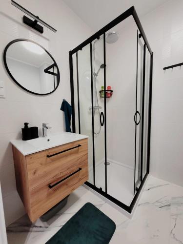a bathroom with a shower and a sink and a mirror at Fresh Apartment Great Location in Białystok
