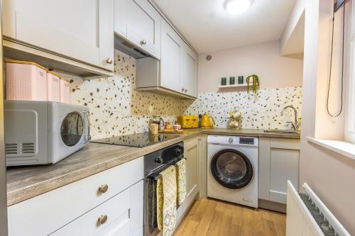 a kitchen with white cabinets and a washer and dryer at City Escape Waterford City Sleeps 6 in Waterford