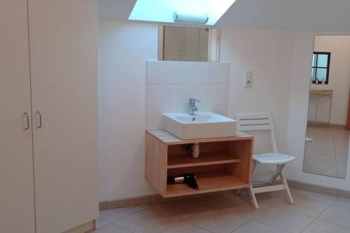 une salle de bain blanche avec un lavabo et une chaise dans l'établissement Maison de campagne avec piscine privée, à Le Guédéniau
