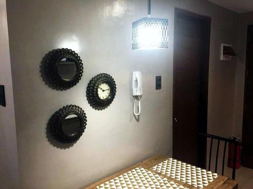 a wall with two mirrors and a clock on a wall at Monte Carlo Residenze in Manila