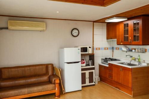 a kitchen with a refrigerator and a couch in it at Jisakke Poongyeong Jeju in Seogwipo