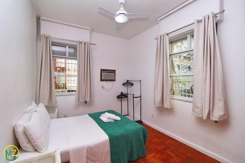 a bedroom with a bed and two windows at Apartamento econômico e espaçoso para 6 pessoas in Rio de Janeiro