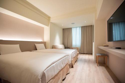 pokój hotelowy z 2 łóżkami i telewizorem w obiekcie Hotel Tainan w mieście Tainan