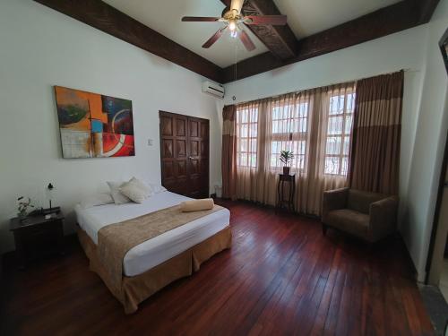 a bedroom with a bed and a ceiling fan and a chair at Hostel Casa Colon in San José