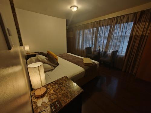 a hotel room with a bed and a table and a window at Hotel Casa Colon in San José