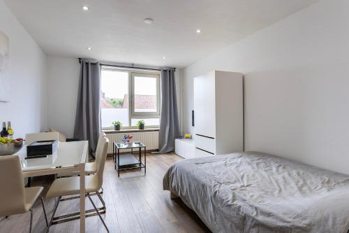 a bedroom with a bed and a desk with a computer at Sunny Studio - Only 5-Min Walk to Sea & Dunes in Wijk aan Zee