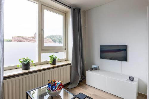 a living room with a tv and a window at Sunny Studio - Only 5-Min Walk to Sea & Dunes in Wijk aan Zee