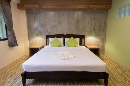 a bedroom with a large white bed with green pillows at K.L. Boutique Hotel in Krabi town