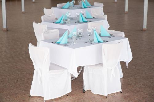 a row of white tables with blue napkins at Dinaburg SPA Hotel in Daugavpils