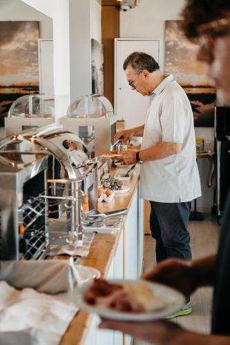 a man standing in a kitchen preparing food at Hotel Villa Sorriso in Lido di Jesolo