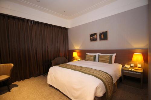 a hotel room with a large bed and two lamps at Grace Hotel Zhonghe in Zhonghe