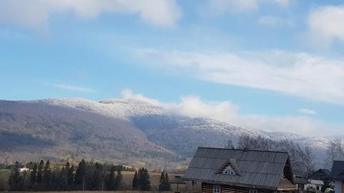 a house in front of a mountain with snow on it at Panskiemisie Domki Całoroczne sauna jacuzzi in Wetlina