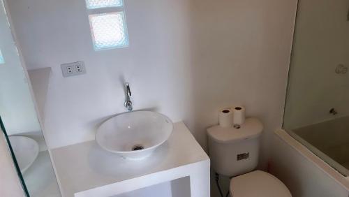 a white bathroom with a sink and a toilet at Yay Lodge SIARGAO, private room 1 with AC & hot shower and fast Starlink Wifi in General Luna