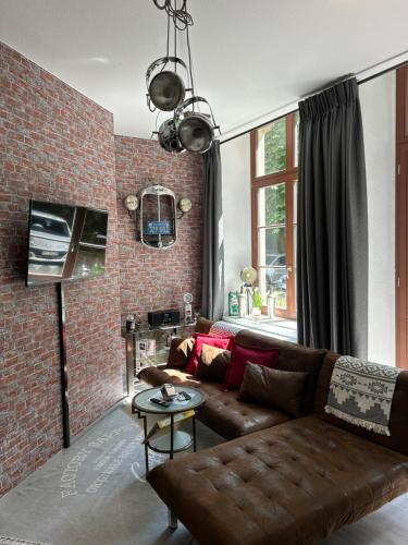 ein Wohnzimmer mit Sofa und Ziegelwand in der Unterkunft Ruhige Wohnung im Fabrikstil in Chemnitz in Chemnitz