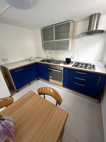 une cuisine avec des placards bleus et une table en bois dans l'établissement Appartamento sul Mare Fano, à Fano