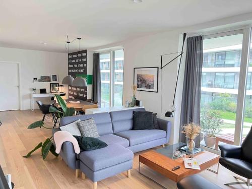 uma sala de estar com um sofá azul e uma mesa em Bo med stil og udsigt til Aarhus lystbådehavn em Aarhus