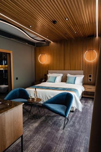a bedroom with a large bed and a blue chair at Hotel Vibre in Cluj-Napoca