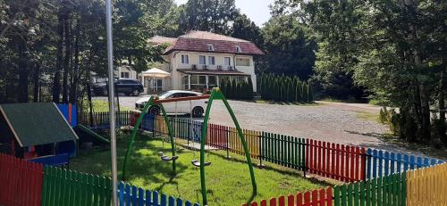 une aire de jeux en face d'une maison avec une clôture colorée dans l'établissement Hotel & Restaurant Kotel, à Kotel