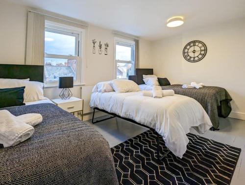 1 dormitorio con 2 camas y reloj en la pared en Charming 3BR in Trendy Tottenham Neighborhood, en Londres