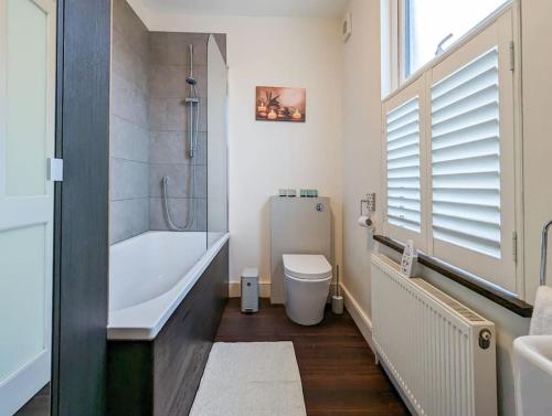 y baño con bañera, aseo y lavamanos. en Charming 3BR in Trendy Tottenham Neighborhood, en Londres