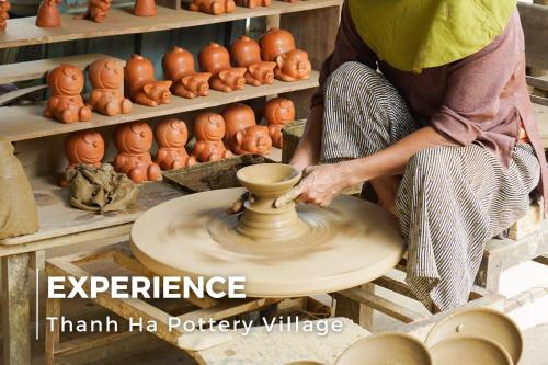 a woman making a vase on a pottery wheel at La Charm Hoi An Hotel & Spa in Hoi An