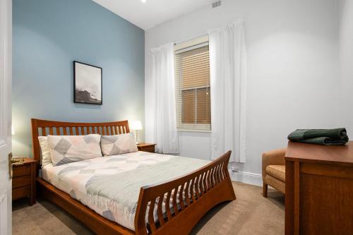 a bedroom with a bed and a desk and a window at Beachside Cottage Glenelg Sth in Glenelg