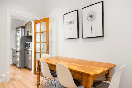 a dining room with a wooden table and white chairs at Beachside Cottage Glenelg Sth in Glenelg