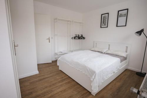 a white bedroom with a white bed and wooden floors at Wohnen am Park in Lübeck