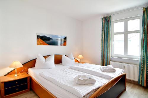 Schlafzimmer mit einem Bett mit weißer Bettwäsche und einem Fenster in der Unterkunft Miramar App. 21 in Ahlbeck