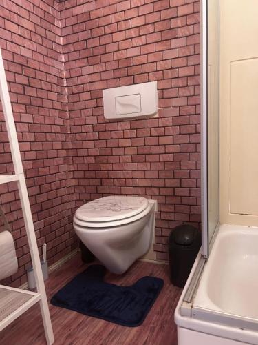 a bathroom with a white toilet and a brick wall at Piano Apartment Halle Center - Netflix- Free WiFi 3 in Halle an der Saale