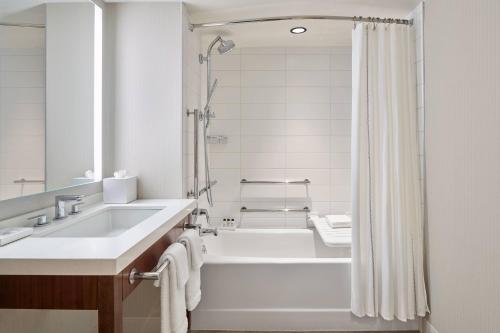 a white bathroom with a tub and a sink at Delta Hotels by Marriott Denver Thornton in Westminster