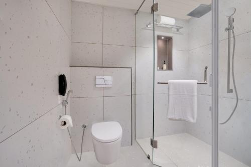 a bathroom with a shower and a toilet and a phone at Lemon Tree Hotel, Rajkot in Rajkot