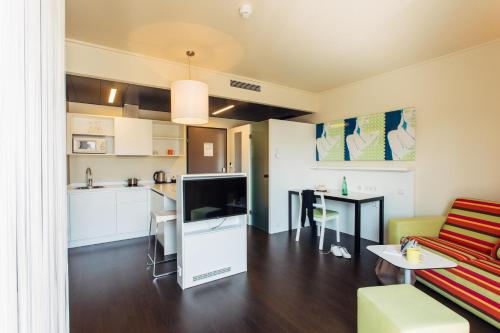 ein Wohnzimmer mit einem Sofa und einem TV sowie eine Küche in der Unterkunft harry's home hotel & apartments in Graz