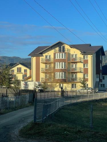 a yellow apartment building with a fence in front of it at Complex Turistic Constantin Bucovina in Câmpulung Moldovenesc