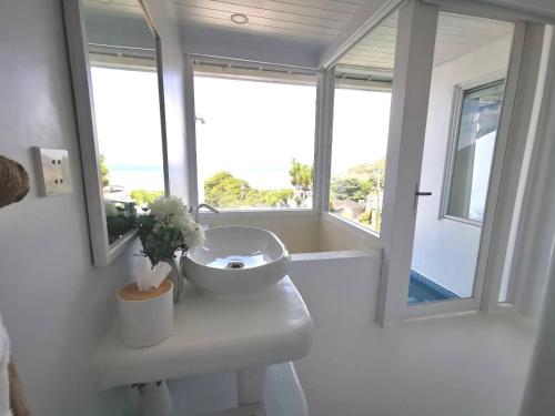 a white bathroom with a sink and a window at Ample Villa 小希臘民宿 in Ruifang