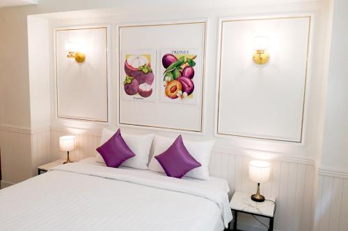 バンコクにあるRose Apple Hotelのベッドルーム(紫色の枕が付いた白いベッド付)