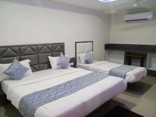 2 große Betten in einem Zimmer mit Kamin in der Unterkunft HOTEL RK VILLA in Vadodara