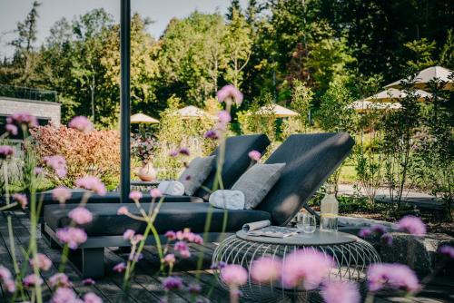 a garden with a couch and a table and flowers at Luisenhöhe - Gesundheitsresort Schwarzwald in Horben