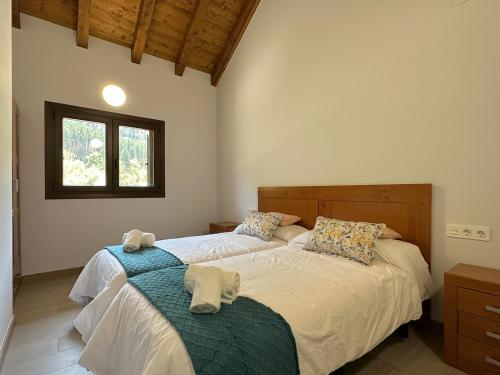 1 dormitorio con 2 camas y ventana en Apartamentos Rurales AINARIAK, en Burgui