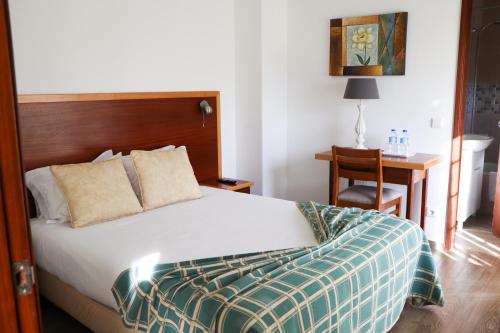 a bedroom with a bed and a desk with a chair at Hotel Louro in Óbidos