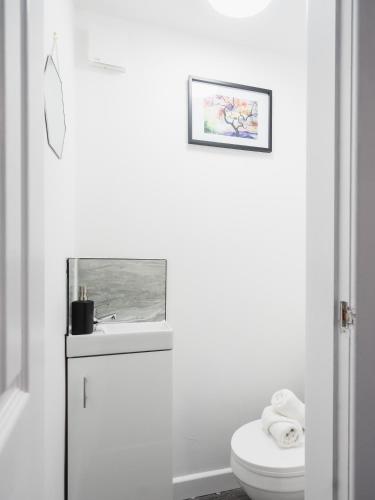 a white bathroom with a toilet and a sink at Comfy Spacious Home Near Preston City Centre - Sleeps 6 in Samlesbury