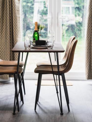 a table with a bottle of wine and two chairs at Comfy Spacious Home Near Preston City Centre - Sleeps 6 in Samlesbury