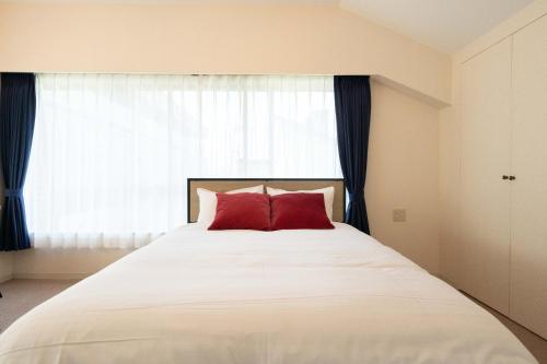a bed with two red pillows in front of a window at Fujiterrace Yoga in Tokyo