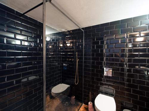 ein schwarz gefliestes Bad mit einem WC und einer Dusche in der Unterkunft Sincai 20 in Bistriţa