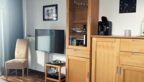 - un salon avec une télévision à écran plat et une chaise dans l'établissement Ferienwohnung De Drückdaal, à Dorum