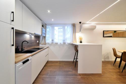 a kitchen with white cabinets and a sink and a table at Optima Apartment Zagreb - Spacious Central Stay in Zagreb