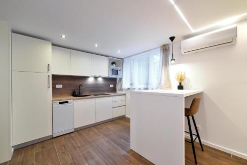 a kitchen with white cabinets and a counter and a window at Optima Apartment Zagreb - Spacious Central Stay in Zagreb