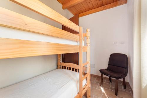 a bedroom with two bunk beds and a chair at Villa Is Sorrisi in Gonnesa