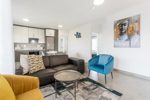 a living room with a couch and a blue chair at Ballito Village Luxury Apartments in Ballito
