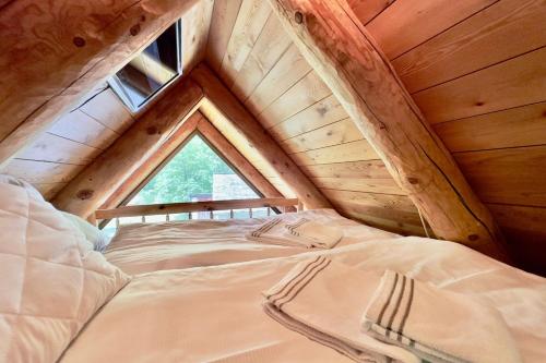 a bed in a wooden attic with a window at Rustico Savinera - Happy Rentals in San Carlo